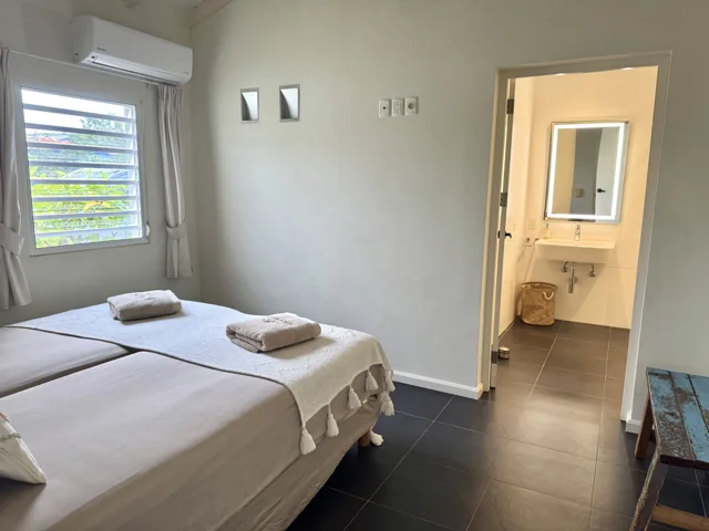 Slaapkamer 3 met tweepersoonsbed, airco en doorkijk naar de eigen badkamer